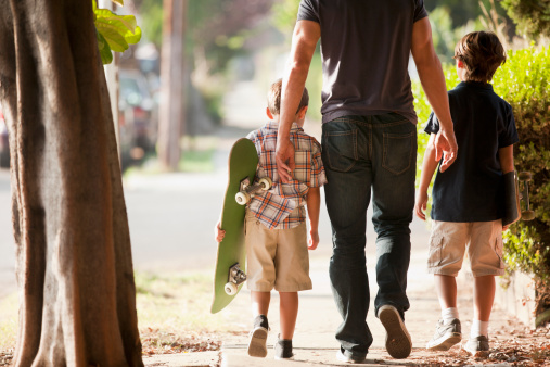 Father and sons walking on suburban street